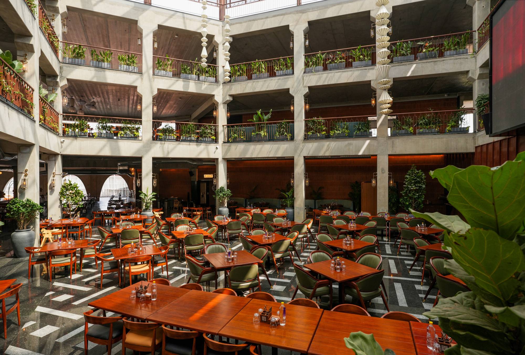 Three-floor atrium dining hall at Legacy Brewing Company with vertical gardens and arched stone architecture