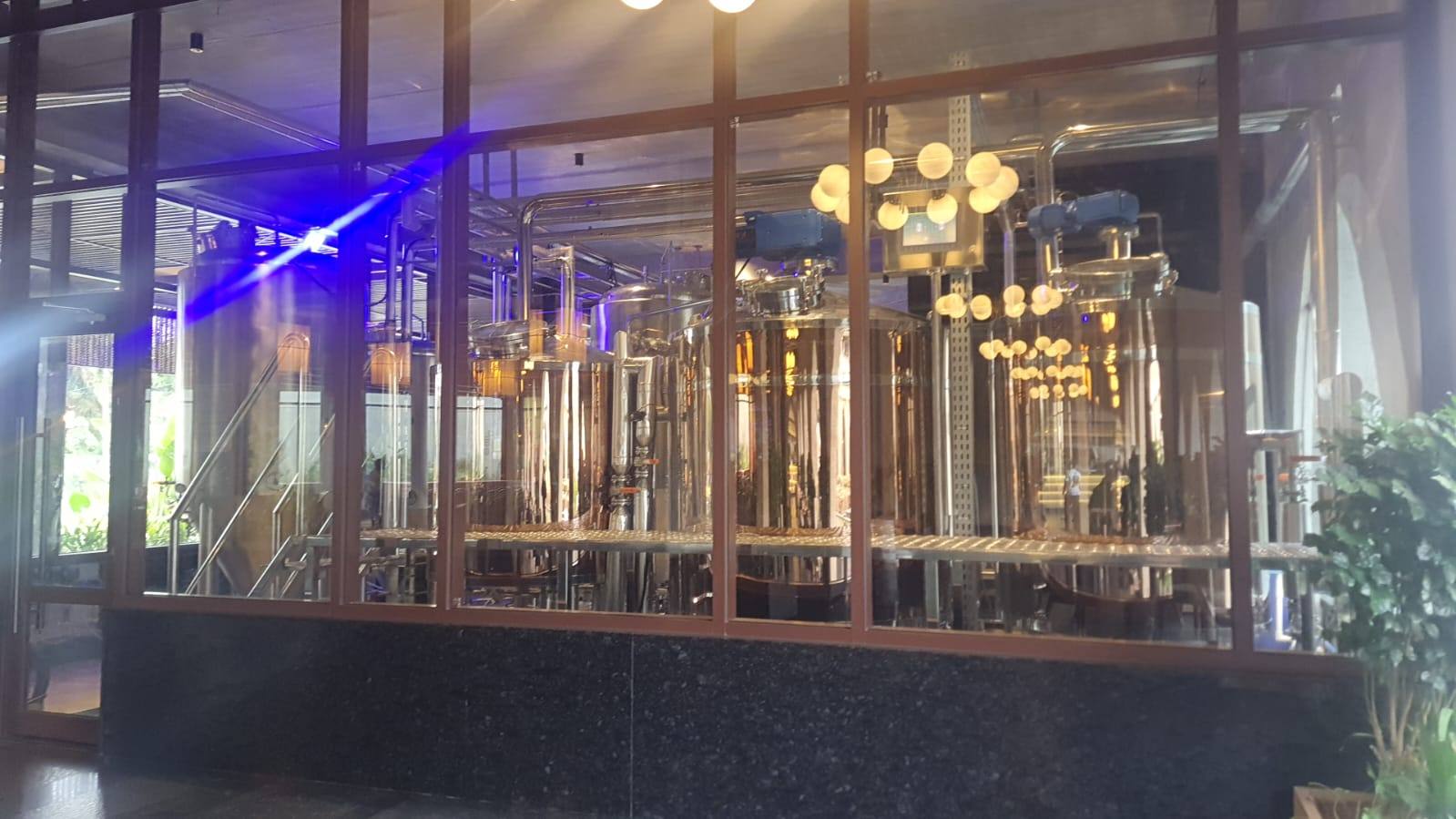 Legacy Brewing Company's in-house brewing tanks, visible behind glass at the venue