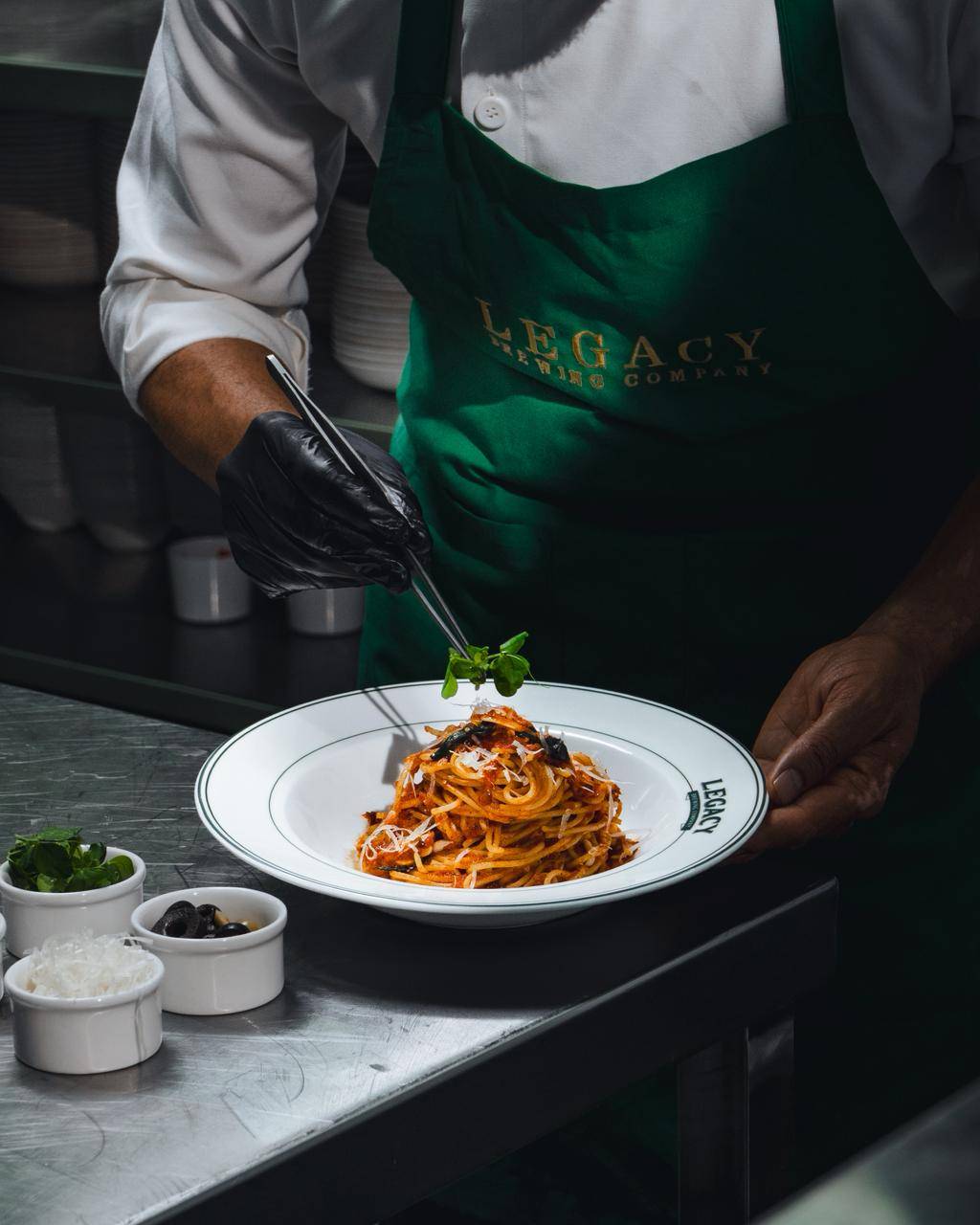 Legacy Brewing Company chef plating fresh pasta in the open kitchen