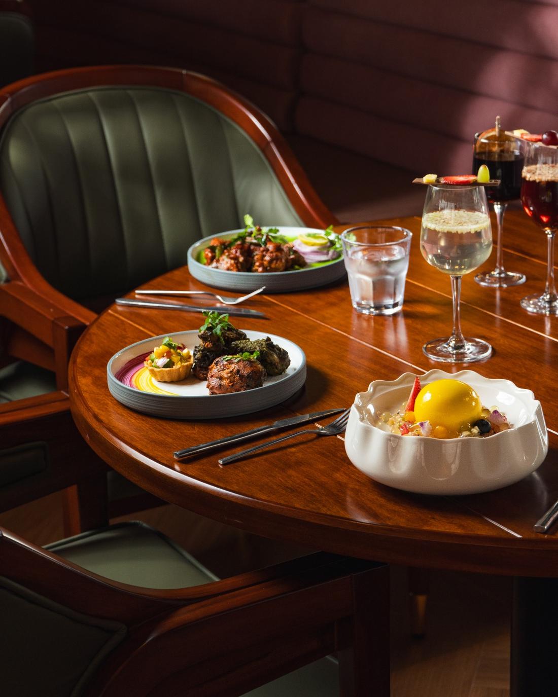 Shared table spread of dishes and cocktails
